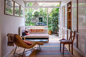 Wohnraum mit Rattanliege und Blick in den Garten