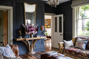 Living room with dark blue walls and console overlooking the dining room