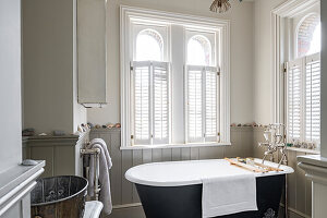 Free-standing black bathtub in the bright, classically furnished bathroom