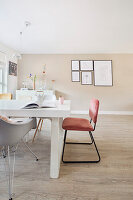 Dining area with white table, pink chair and picture wall