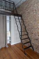 Metal ladder to the open gallery with brick wall