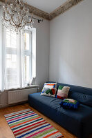 Blue sofa with colourful cushions and striped carpet in an elegant old room