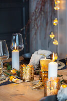 Wooden table decorated for Christmas with candles and fairy lights in the background