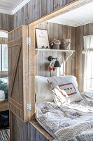 Wooden wall sleeping alcove with decorative shelf and reading lamp
