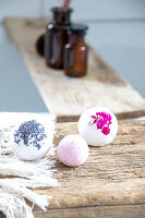Three different coloured bath bombs on a rustic wooden surface