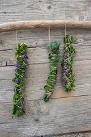 Three tied bunches of herbs to dry on a wooden wall