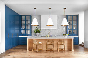 Kitchen with blue cabinets and wooden cooking island with rattan bar stools