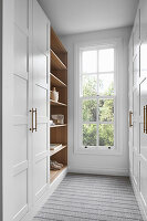 Fitted wardrobe with white doors and wooden shelves in the dressing room