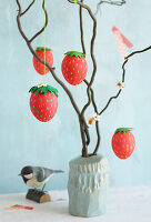 DIY Easter eggs in strawberry design hung on branches