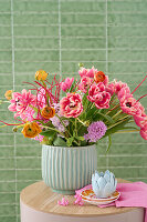 Spring bouquet with tulips (Tulipa) and ranunculus in a fluted vase on a wooden table