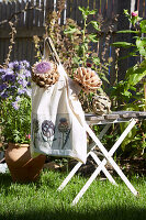 Stofftasche mit Artischockenmotiv auf Gartenstuhl im Freien