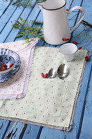 Self-sewn placemats with rose motif and ruffles on a blue wooden table