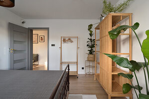 Bedroom with wooden floor, plants and open wardrobe made of bamboo