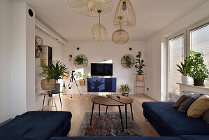 Living room with blue sofa, wooden tables, golden lamps and plants