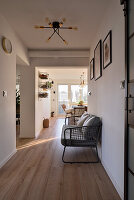 Long hallway with wooden floor, modern bench with upholstery and retro-style ceiling light