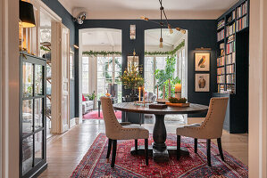 Essbereich mit dunkler Wandfarbe, antikem Holztisch und Orientteppich