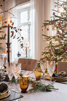Dining table set for Christmas with a Christmas tree in the background