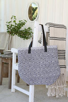 Self-sewn bag made from rag rug hangs on white chair