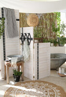DIY screen in front of bathtub, wash bowl and plants, boho style