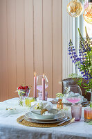 Spring table setting with lupins and pink candles in the dining room