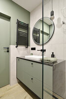 Modern bathroom with light green washbasin and round mirror