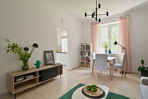 Two-room flat with modern furniture, light-coloured curtains and green accents