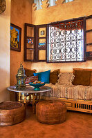 Moroccan lounge with leather seats in front of ornate window grilles