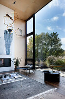 Modern living area with large window front, abstract wall art and geometric hanging lamp