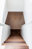 Modern wooden staircase with white walls in a minimalist design