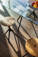 Glass table on wooden floor with modern stools and fruit bowl