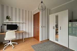 Modern home office with grey-striped wallpaper and wooden floor