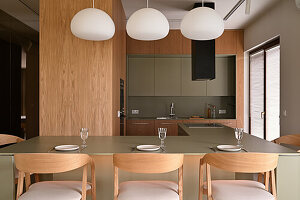 Open-plan kitchen with modern wood panelling and hanging lamps