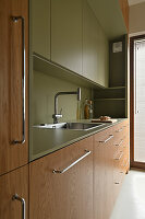 Compact kitchen with green splashback and wooden fronts
