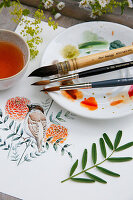 Watercolour painting with sparrow and marigolds, brush and paints on palette