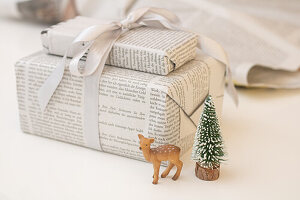 Gifts wrapped in newspaper with a deer figure and mini Christmas tree
