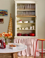 Open kitchen cupboard with crockery and red cooking pots
