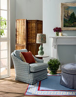 Patterned upholstered armchair in the living room with rattan screen