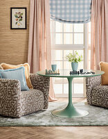Runder, mintfarbener Tisch zwischen gemusterten Sesseln im Wohnzimmer