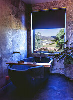 Free-standing bathtub in modern bathroom with large window view