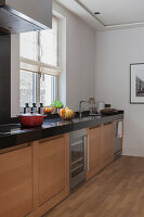 Moderne Küche mit schwarzer Arbeitsplatte und hellen Holzfronten