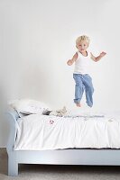 Little boy jumping on his bed
