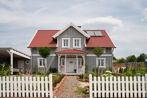 Graues zweistöckiges Einfamilienhaus mit einer Gaube und einem roten Dach im nordischen Stil mit Holzfassade, Korbach, Hessen, Deutschland, Europa