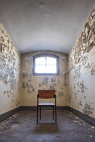Old prison cell with peeling paint and chair, former district court prison in Berlin Koepenick, Germany