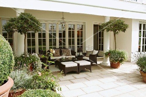 Braune Outdoormöbel auf Steinboden einer Terrasse mit Säulen und ... Braune Outdoormöbel auf Steinboden einer Terrasse mit Säulen und ...