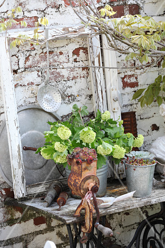 Ornaments On Old Sewing Machine Table Against Garden Wall Bild