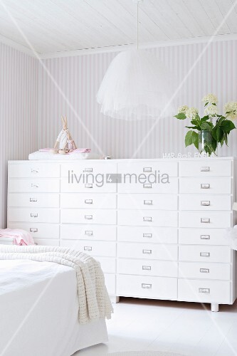 Pendant Lamp With Tulle Lampshade And Chest Of Drawers Against Pale Pendant Lamp With Tulle Lampshade And Chest Of Drawers Against Pale Striped Wallpaper In Bedroom