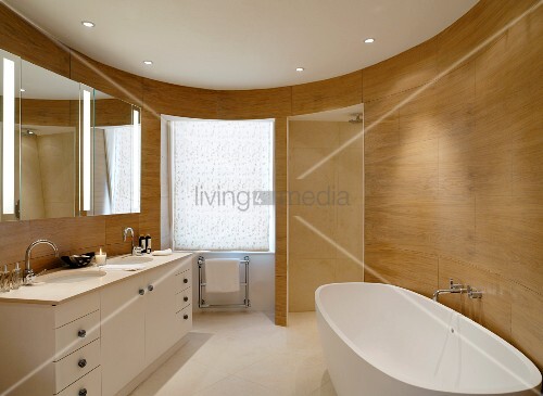 Freistehende Wanne in ovalem, modernen Bad mit holzverkleideter Wand ... Freistehende Wanne in ovalem, modernen Bad mit holzverkleideter Wand ...