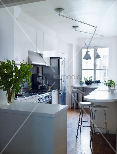 Offene Küche mit schwenkbaren Deckenlampen über weisse Theke an Wand ... Offene Küche mit schwenkbaren Deckenlampen über weisse Theke an Wand ...
